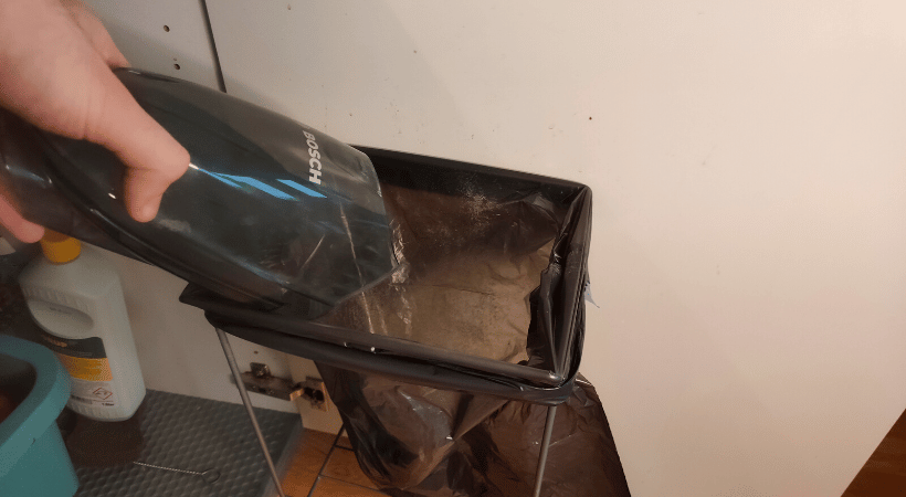 emptying bagless vacuum container into the trash bag