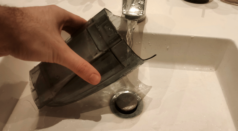 bagless vacuum container being washed under the hot tap water