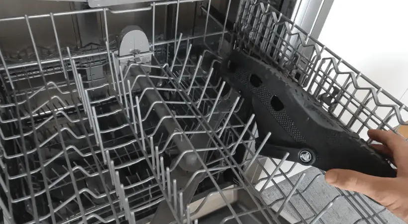 A black croc being placed on the upper rack of the dishwasher