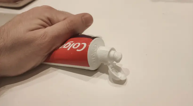 a hand squeezing a tube of toothpaste