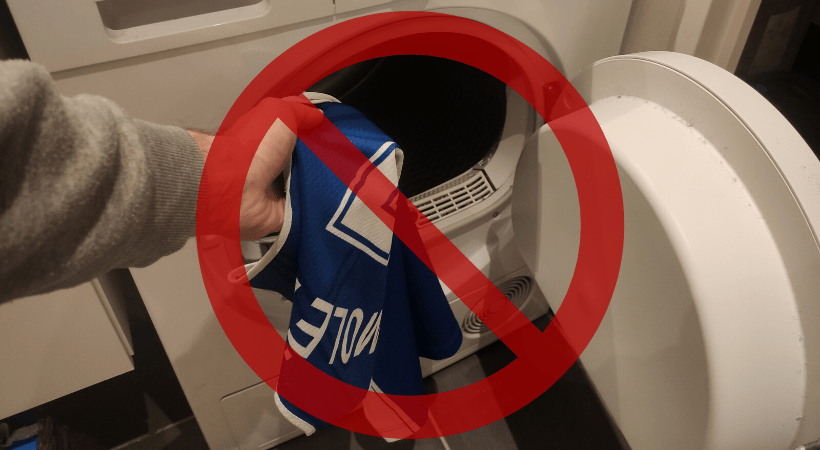 Cleanerd member's hand putting a sports jersey into a tumble dryer with a no sign as overlay.