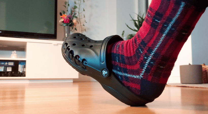 Foot with socks on wearing Crocs